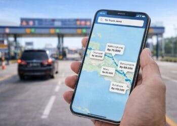 Seorang pengemudi menggunakan smartphone untuk melakukan cara cek tarif tol arus balik 2026