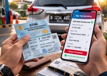 Seorang pria sedang memegang STNK baru dan melakukan update data di aplikasi MyPertamina