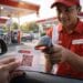 Seorang pengendara menunjukkan QR Code Pertamina yang sudah dicetak kepada petugas SPBU