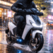 Pengendara motor listrik yang tetap melaju dengan aman di atas aspal basah setelah hujan berkat sistem isolasi kelistrikan yang kedap air.