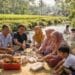 Keluarga besar piknik bersama di tepi sungai desa yang asri saat libur lebaran