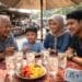 Keluarga sedang menikmati kuliner viral Medan dengan perlindungan dari cuaca panas ekstrem.