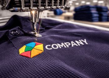 Detail proses bordir kaos Medan menggunakan mesin komputer canggih untuk menyematkan logo presisi pada kemeja polo shirt.