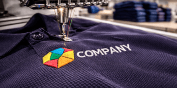 Detail proses bordir kaos Medan menggunakan mesin komputer canggih untuk menyematkan logo presisi pada kemeja polo shirt.