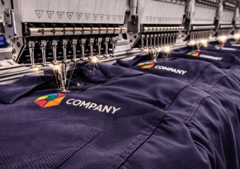 Proses produksi massal menggunakan mesin komputer canggih pada layanan bordir seragam Medan untuk kemeja kerja kantor.