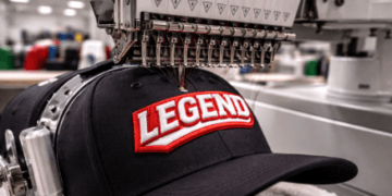 Mesin bordir komputer khusus sedang mengerjakan desain logo timbul pada layanan bordir topi Medan.