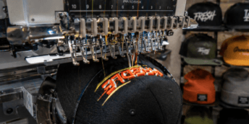 Proses pengerjaan bordir timbul (3D) pada topi baseball menggunakan mesin digital di pusat bordir topi satuan Medan.