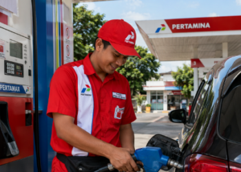 pegawai pertamina sedang melakukan pelayanan kepada penbeli bahan bakar