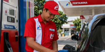 pegawai pertamina sedang melakukan pelayanan kepada penbeli bahan bakar