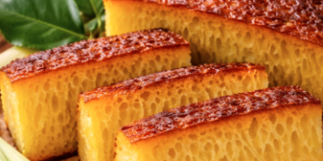 Tekstur bersarang yang sempurna pada sepotong Bika Ambon Medan yang berwarna kuning keemasan.