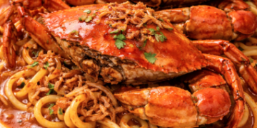 Satu porsi Mie Aceh Medan Terenak dengan topping kepiting besar dan kuah kental kemerahan.