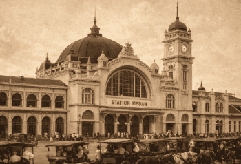 Foto bersejarah Stasiun Kereta Api Medan pada masa kolonial Belanda dengan gaya arsitektur yang megah.