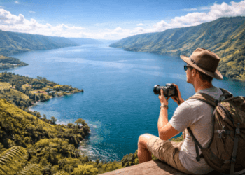 Wisatawan sedang mengabadikan momen di salah satu spot foto di Danau Toba yang memiliki pemandangan lanskap spektakuler.
