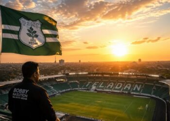 A breathtaking sunrise over the newly renovated Teladan Stadium. The PSMS Medan flag waves proudly at the highest point. Golden hour lighting, cinematic, high resolution, 8k, no blur.