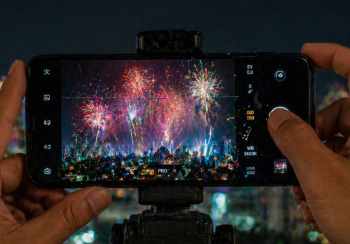 Seorang warga sedang mempraktikkan tips fotografi HP untuk mendapatkan Foto Kembang Api di Medan yang sempurna.