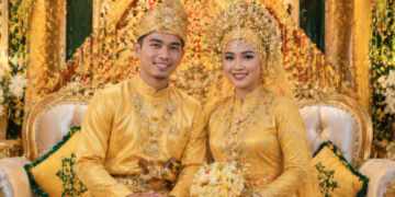 Pasangan pengantin yang tampil anggun dalam balutan busana Pernikahan Adat Melayu Medan.