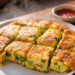Potongan tebal yang memperlihatkan tekstur empuk dari hidangan Resep Martabak Telur Simpel dengan isian daun bawang dan cabai.