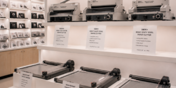 Jajaran tempat pemotong kertas bahan besi baja tebal untuk usaha fotokopi dan alat paper cutter trimmer minimalis berbagai ukuran panjang papan yang tersusun sangat rapi di dalam etalase toko perlengkapan kantor