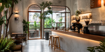 Suasana dalam ruangan cafe modern yang estetis dengan jajaran kursi kayu dan tanaman hijau di salah satu cafe di Medan