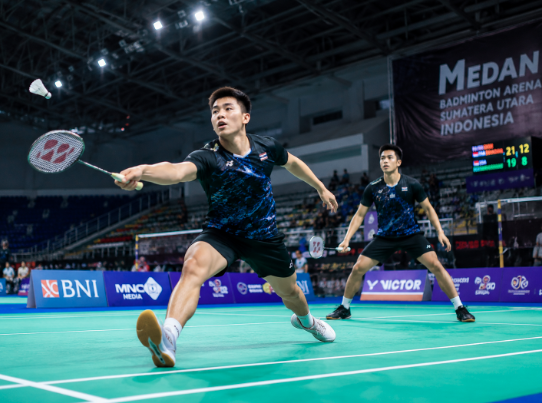 Suasana dalam ruangan gedung olahraga bulu tangkis dengan lapisan lantai karpet hijau yang bersih di salah satu lapangan badminton di Medan