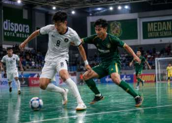 Aktivitas anak muda saat menendang bola di atas lantai matras hijau yang bersih di salah satu lapangan futsal di Medan