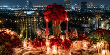 Keindahan tatanan meja makan malam romantis dengan lilin menyala dan latar belakang kerlip lampu kota di salah satu tempat dinner romantis di Medan