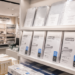 Jajaran tempat plastik laminating bahan poliester jernih untuk pengaman dokumen dan alat laminating pouch film minimalis berbagai ukuran mika yang tersusun sangat rapi di dalam etalase toko perlengkapan kantor