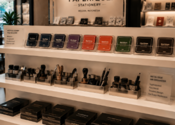 Jajaran tempat bak stempel meja berbahan akrilik mewah dan wadah tinta cap minimalis yang tersusun sangat rapi di dalam etalase toko perlengkapan kantor