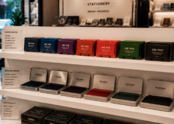Jajaran bak stempel meja model wadah tertutup bahan plastik tebal dan alat bantalan cap flash otomatis warna-warni yang tersusun sangat rapi di dalam etalase toko perlengkapan kantor