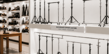 Jajaran tempat tiang background logam tebal model tripod untuk studio foto dan alat stand backdrop foto minimalis berbagai ukuran panjang yang tersusun sangat rapi di dalam etalase toko perlengkapan kamera